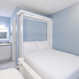 The master suite features a pull-down queen murphy bed, a stylish vanity leading to the bathroom, and a calming blue color scheme