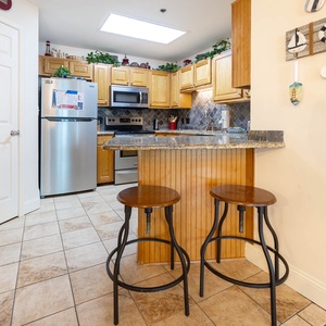 Enjoy casual meals at the kitchen bar, surrounded by warm wood cabinetry and inviting decor