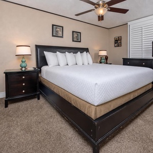 The master bedroom features a plush king bed, elegant decor, and a TV, with a serene view of the beach from the balcony