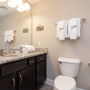 Enjoy a relaxing shower after a day at the beach in this guest bath with stylish accents and fluffy towels