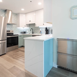 Elegant kitchen with modern appliances, sleek cabinetry, and compact fridge-freezer for extra cold storage