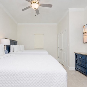 Cozy guest room featuring two comfortable queen beds, a large TV, and stylish blue accents for a relaxing stay
