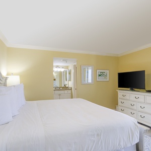 Brightly colored walls in the master suite complement the king bed, while a flat-screen TV and adjacent bath enhance the vibe
