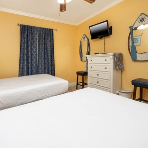 This cheerful guest room features two queen beds, nautical decor, a TV, and a dresser for your convenience