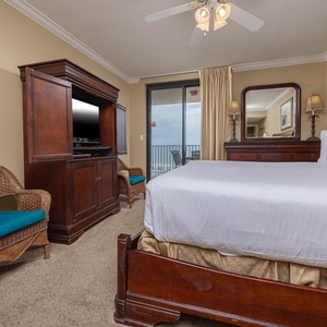 Relax in the inviting master bedroom featuring a king bed, a cozy chair, and easy access to the balcony with beautiful views