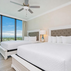 Relax in this guest bedroom with two queen beds, large windows with stunning beach views, and stylish decor