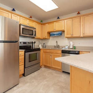 The modern kitchen features warm wood cabinetry, sleek stainless appliances, and a convenient breakfast bar for casual dining