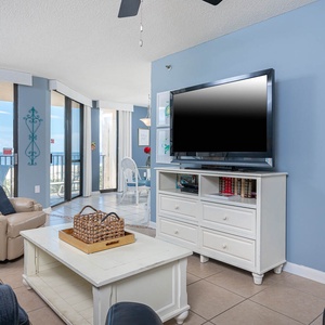Relax in the inviting living area featuring a large TV, cozy sofa with queen sleeper, and a beachfront view