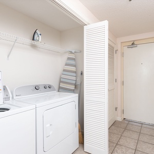 Laundry area featuring a washer and dryer, with an iron and ironing board neatly stored on a shelf for convenience