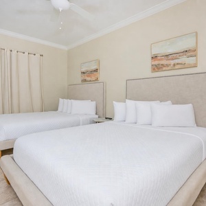 Inviting guest bedroom with two queen beds, soft linens, and artwork that adds a touch of charm