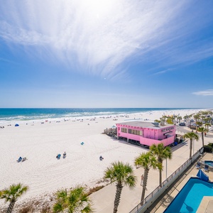 Sunlight sparkles on the coastline as you watch lively beachgoers from your balcony