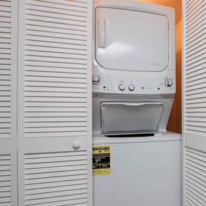 This laundry area features a stacked washer and dryer behind white louvered doors for your convenience during your stay