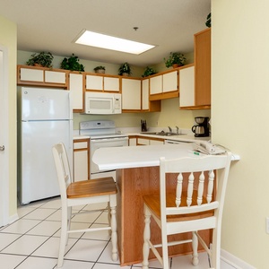 Bright kitchen area featuring white cabinetry, a breakfast bar with seating, and a coffee maker for convenient morning brews