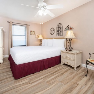 This guest bedroom has a queen bed, wicker furniture, and soft lighting, creating a relaxing retreat