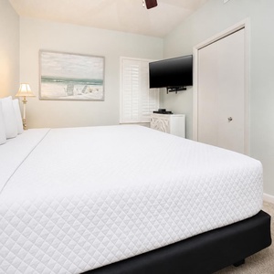 Tranquil bedroom featuring a king bed, soft lighting, and beach artwork for a coastal vibe