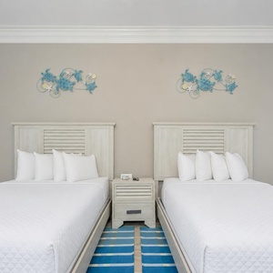 Dual queen guest room with playful sea turtle wall accents and soft linens