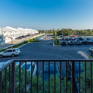 Enjoy the view from the master balcony overlooking the parking area and lush greenery, perfect for a relaxing moment
