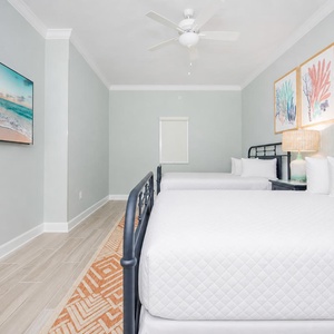 Rest in this cozy bedroom featuring two queen beds, vibrant artwork, and a lamp that adds a warm glow to your stay