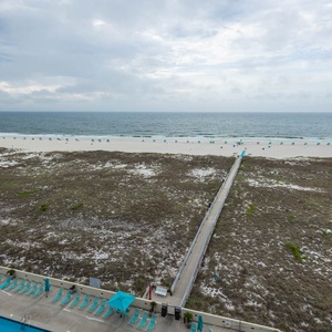 Expansive view of the beach with turquoise umbrellas lining the shore, leading to the gentle waves of the Gulf