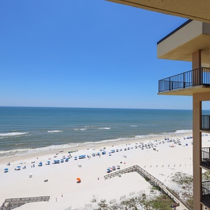 Enjoy stunning views of the serene beach and vibrant umbrellas from your private balcony in this inviting coastal retreat