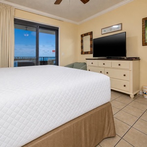 Master bedroom featuring a plush king bed, flat-screen TV, and balcony access on the beach