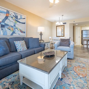 Living area features a blue sofa with queen sleeper, a glass-top coffee table, and a dining space