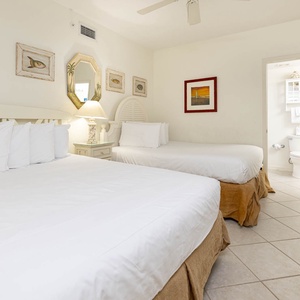 Relax in this inviting guest bedroom featuring two comfortable queen beds, coastal decor, and a bright atmosphere