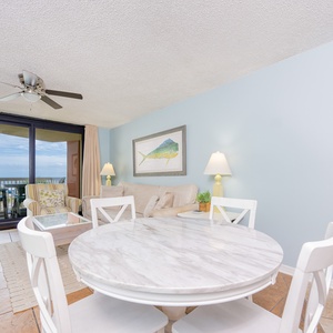 Dining and living area features a cozy sofa, marble dining table, and a lovely view through sliding glass balcony doors