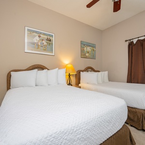 Experience restful nights in this cozy guest bedroom with two comfortable double beds, soft lighting, and charming artwork