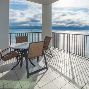 This inviting balcony features a table and chairs, perfect for enjoying stunning beachfront views from the fifteenth floor