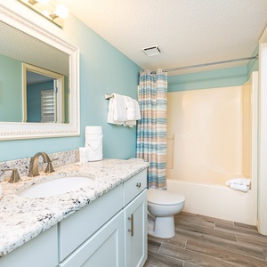 Granite countertop gleams as you prepare for the day in the guest bath with soft blue walls and fresh towels