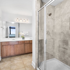 The master bath features a spacious walk-in shower and a stylish double vanity with a view of the beachfront