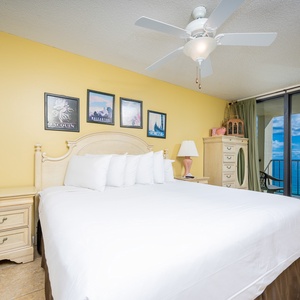 Master bedroom with a plush king bed and a stunning view from the balcony through large glass doors