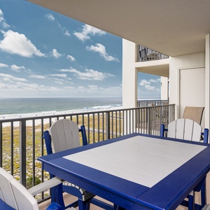 Balcony with a blue and gray table set offers a direct view of the beach and gulf, perfect for relaxing outdoors