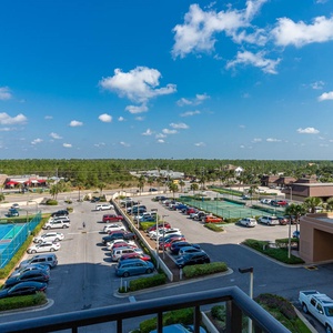 Master balcony view showcases a vibrant tennis court and lush greenery under a bright blue sky