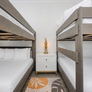 Guests can relax in this bunk room featuring two double over queen bunks, soft linens, and a stylish lamp