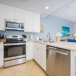 This kitchen features stainless appliances, granite countertops, and a view of the inviting beachfront through large windows