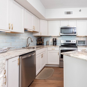 The kitchen features stainless appliances, granite countertops, and a charming blue tile backsplash for a refreshing look