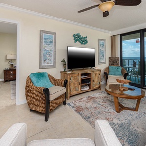 This inviting living area features a large TV, cozy seating with a queen sofa-sleeper, and a beautiful view of the beach