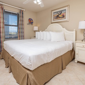 Guest bedroom featuring a large king bed with plush white linens, colorful curtains, and a cozy bedside lamp