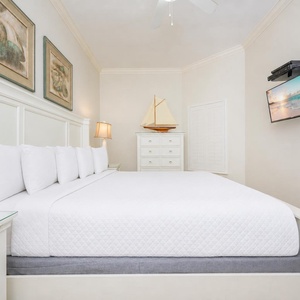 Guest bedroom featuring a plush king bed, nautical decor, and a wall-mounted TV for cozy evenings