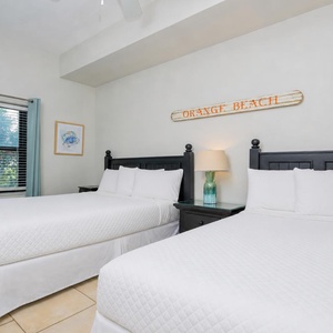 Rest in this guest bedroom featuring two beds, a stylish lamp, and cheerful decor for a relaxing getaway