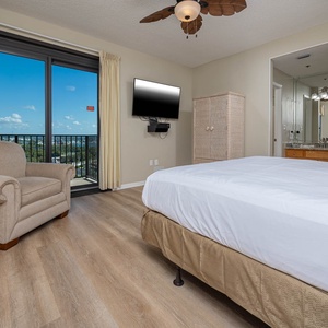 Enjoy the comfort of the master bedroom featuring a king bed, a cozy chair, and a view through sliding balcony doors