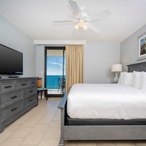 Relax in this inviting master bedroom featuring a king bed, flat-screen TV, and easy access to the balcony with beach views