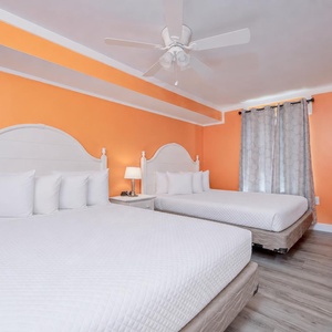 Bright orange walls surround the guest suite with two queen beds ready for restful evenings and TV nights