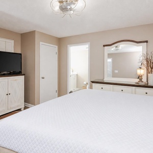 Experience restful nights in this cozy guest bedroom featuring a king bed, a TV, and warm decor for a relaxing stay