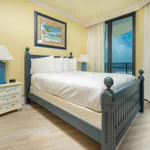 Inviting guest bedroom featuring a plush queen bed, coastal decor, and large windows for fresh air and views