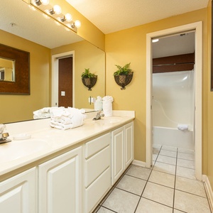 Spacious master bathroom with dual sinks, fresh towels, and a relaxing tub-shower for unwinding