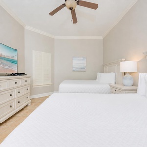 Guest bedroom featuring two comfortable queen beds and a large TV for entertainment