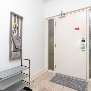 Step into a welcoming entryway adorned with a charming pelican artwork and practical storage for your beach gear